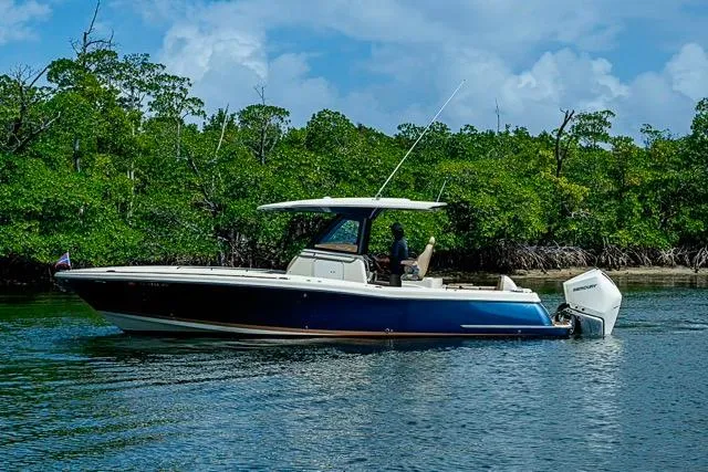 Slide: The Image of 2019 Chris-Craft Catalina 30 boat cruising on a calm river near lush greenery. - 2