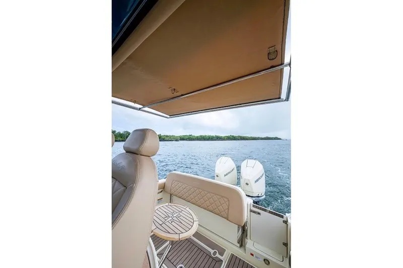 Slide: The Image of 2019 Chris-Craft Catalina 30 boat interior with canopy, seating, and twin outboard motors on water. - 20