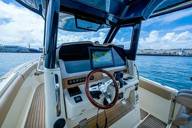 Slide: The Image of 2019 Chris-Craft Catalina 30 boat dashboard with navigation screen, steering wheel, and ocean view. - 25