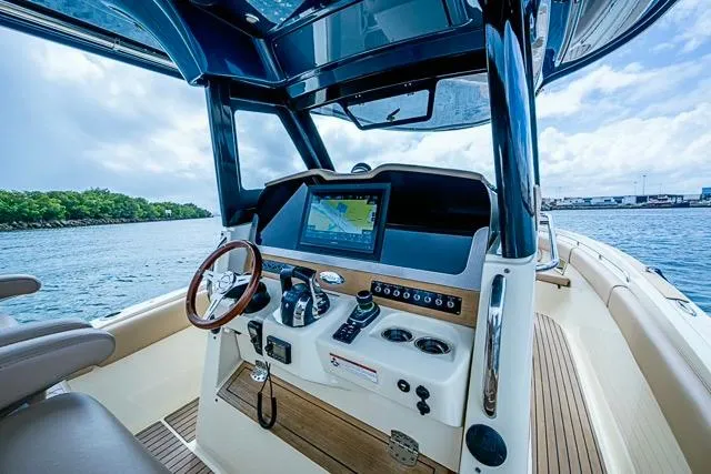 Slide: The Image of 2019 Chris-Craft Catalina 30 helm with navigation display, steering wheel, and controls on open water. - 26