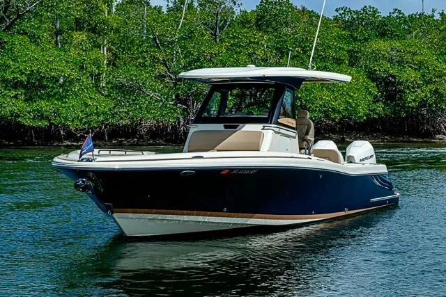 Slide: The Image of 2019 Chris-Craft Catalina 30 boat cruising on a serene waterway with lush greenery. - 3