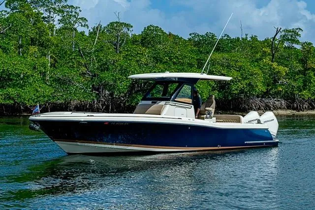Slide: The Image of 2019 Chris-Craft Catalina 30 boat on calm water, surrounded by lush greenery. - 4