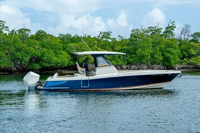 Slide: The Image of 2019 Chris-Craft Catalina 30 boat cruising on calm water near lush greenery. - 40