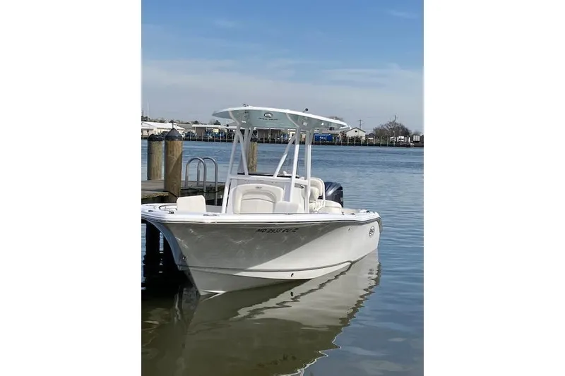 The Image of 2024 Sea Hunt Ultra 219 boat docked on calm water under clear sky. - 0