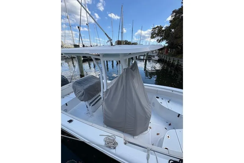 Slide: The Image of 2024 Sea Hunt Ultra 219 boat docked, featuring covered seating and console. - 11