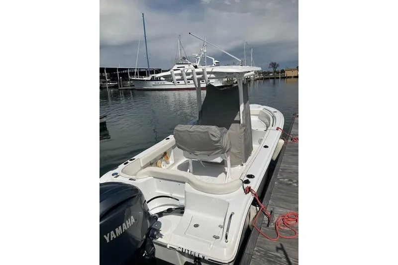 Slide: The Image of 2024 Sea Hunt Ultra 219 boat docked, featuring Yamaha engine, calm marina setting. - 5
