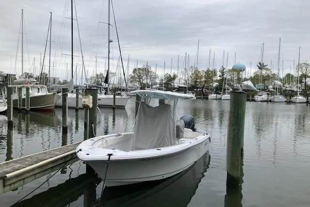 Slide: The Image of 2024 Sea Hunt Ultra 219 boat docked in a marina with sailboats in the background. - 6