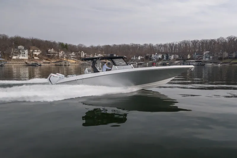 Slide: The Image of 2026 Fountain 38 SCX boat cruising on a calm lake near waterfront homes. - 2