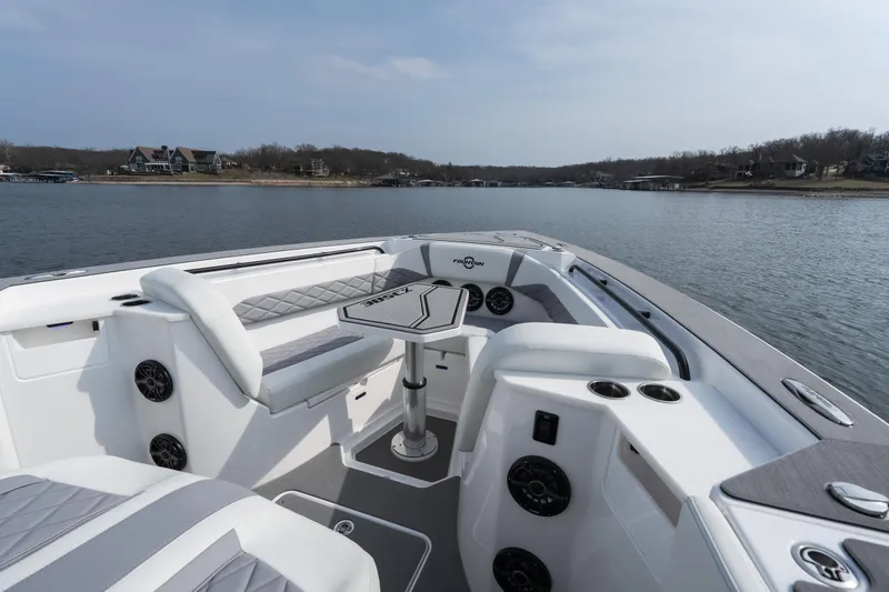 Slide: The Image of 2026 Fountain 38 SCX boat interior with seating and table on a calm lake. - 32