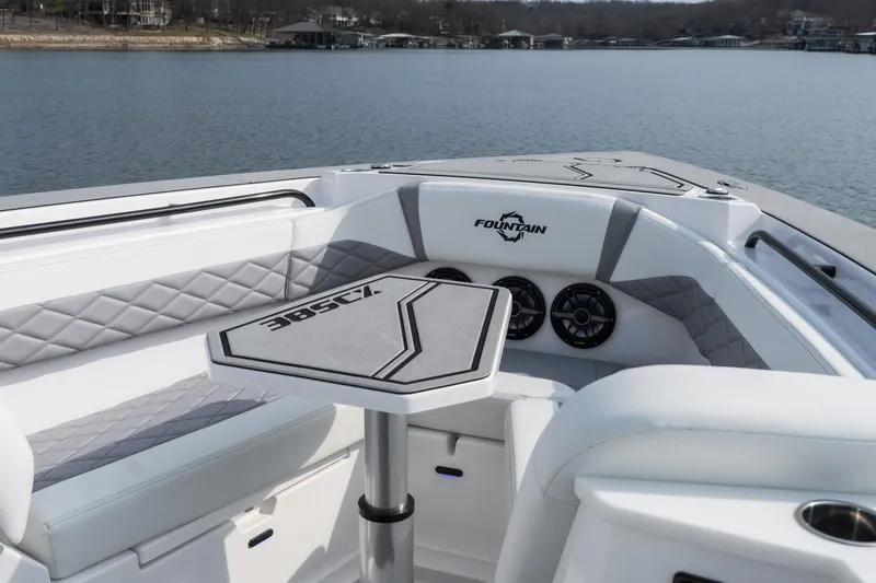 Slide: The Image of 2026 Fountain 38 SCX boat interior with seating and table on a calm lake. - 33