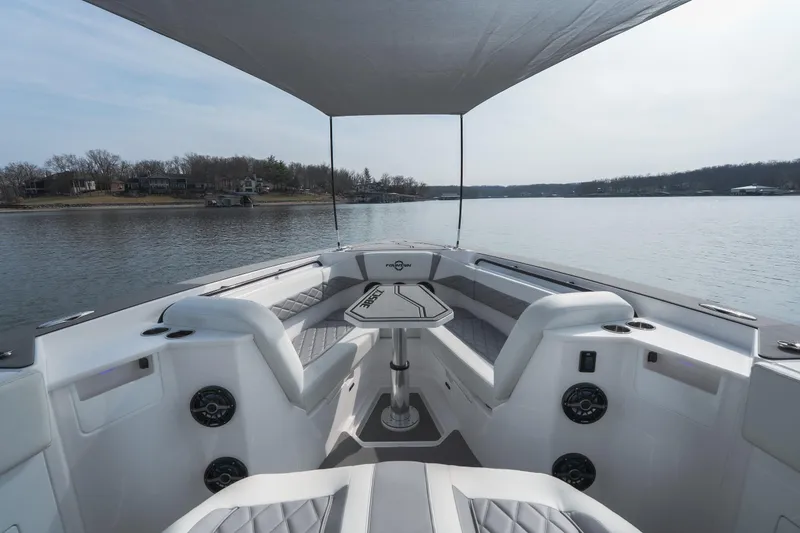 Slide: The Image of 2026 Fountain 38 SCX boat interior with seating and table on a calm lake. - 46