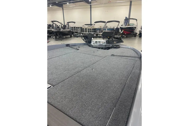 Slide: The Image of 2023 Triton 21 XrT boat with spacious carpeted deck in showroom. - 13