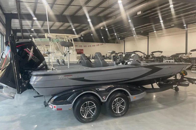 Slide: The Image of 2023 Triton 21 XrT boat in showroom, sleek design, dual axle trailer. - 7
