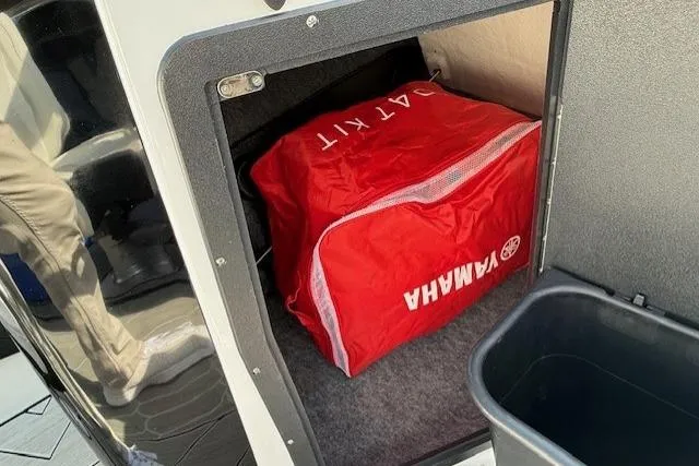 Slide: The Image of Storage compartment of 2023 Yamaha Boats 222XE with red Yamaha bag inside. - 20