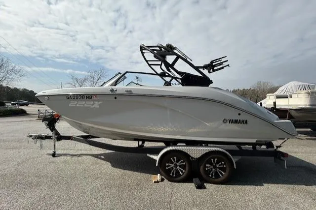Slide: The Image of 2023 Yamaha Boats 222XE on trailer, side view, parked outdoors under cloudy sky. - 3