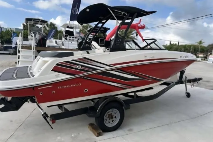 The Image of 2023 Bayliner VR5 Bowrider I/O boat in red and white on a trailer, outdoor display. - 1