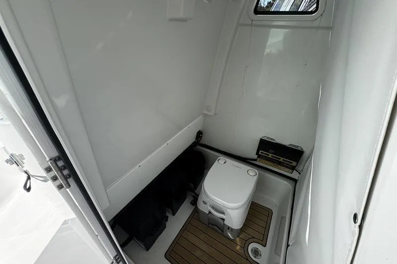 Slide: The Image of 2026 Sportsman Masters 247 Bay Boat interior with compact marine toilet. - 20