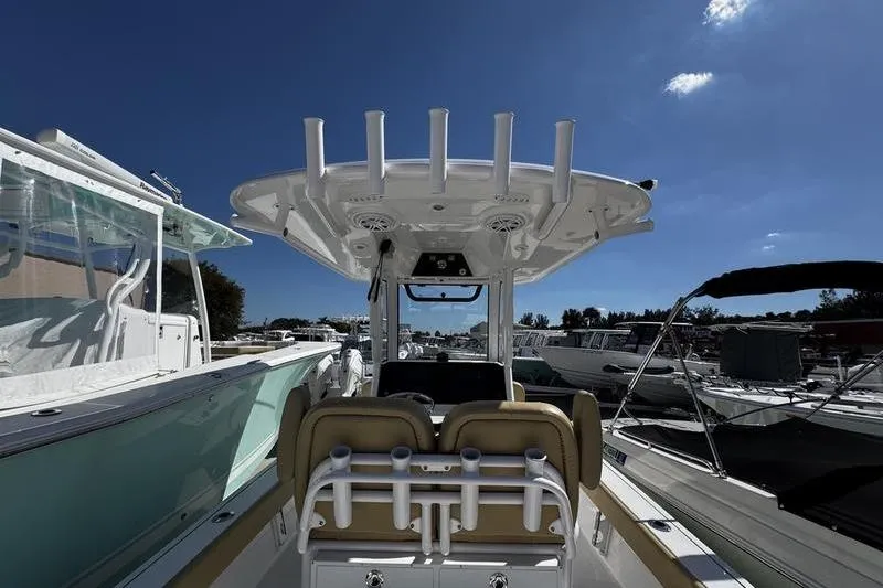 Slide: The Image of 2026 Sportsman Masters 247 Bay Boat interior with rod holders and seating under clear blue sky. - 26