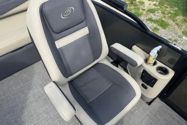 Slide: The Image of Captain's chair in 2022 Barletta Cabrio 22UC boat, featuring cup holder and cleaning spray. - 13