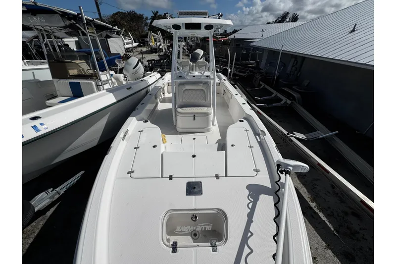 Slide: The Image of 2021 Blue Wave 2600 PureBay boat, white deck, parked in marina under cloudy sky. - 10