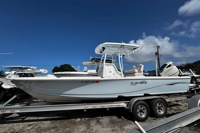 Slide: The Image of 2021 Blue Wave 2600 PureBay boat on trailer under clear blue sky. - 23