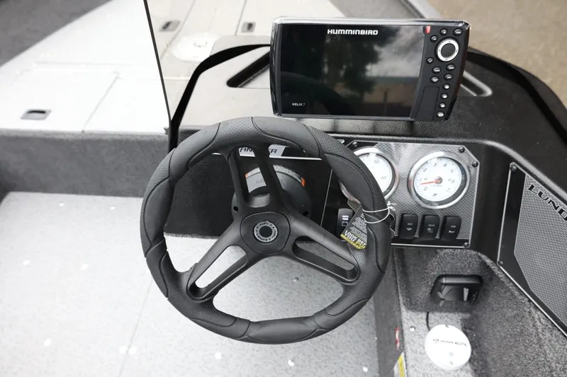 Slide: The Image of 2026 Lund 1650 Angler SS dashboard with steering wheel and Humminbird Helix 7 display. - 19