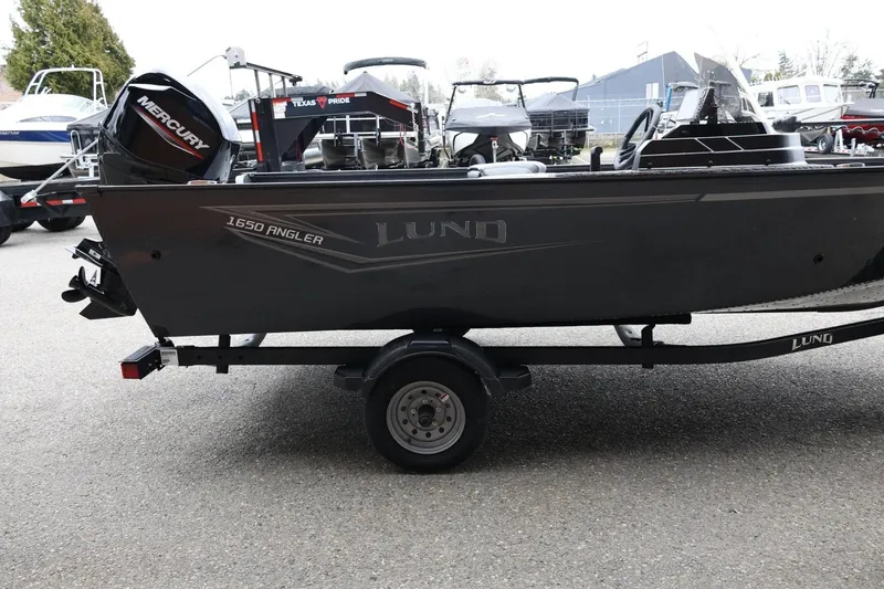 Slide: The Image of 2026 Lund 1650 Angler SS boat on trailer, featuring Mercury engine, parked outdoors. - 5