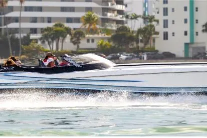 The Image of High-speed MTI 440 boat cruising near modern waterfront buildings, 2025 model. - 1