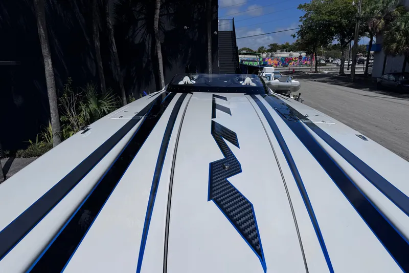 Slide: The Image of 2025 MTI 440 boat with sleek design and bold stripes, parked outdoors. - 19