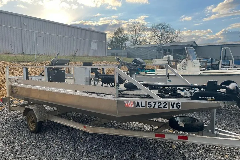 Slide: The Image of 2024 CustomBilt Pondtoon 1672 boat on trailer, parked outdoors under a cloudy sky. - 3