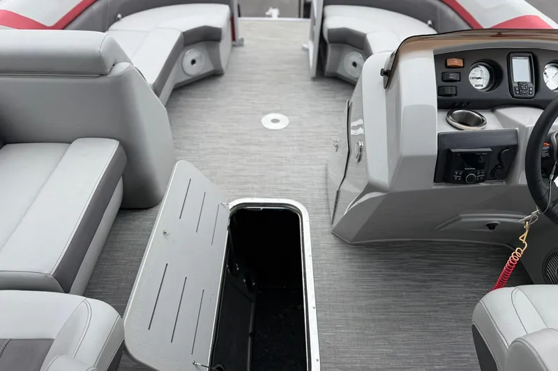 Slide: The Image of 2023 Bennington 22 SX Quad Bench interior with open storage, gray seating, and control panel. - 10