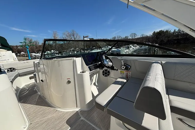 Slide: The Image of 2026 Sea Ray SDX 250 Outboard boat interior with helm and seating under clear blue sky. - 16