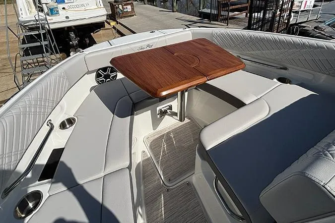 Slide: The Image of 2026 Sea Ray SDX 250 Outboard boat interior with cushioned seating and wooden table. - 24