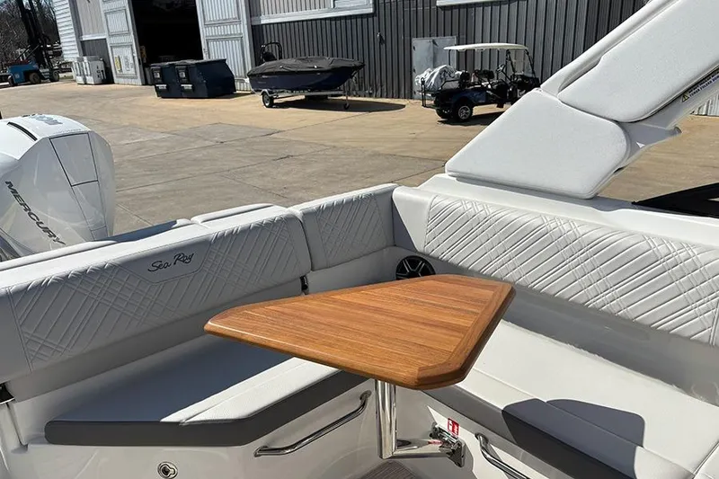 Slide: The Image of 2026 Sea Ray SDX 250 Outboard boat interior with wooden table and cushioned seating. - 26
