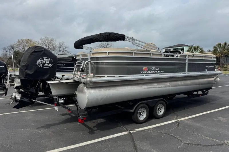The Image of 2024 Sun Tracker Party Barge 24 DLX pontoon boat on trailer in parking lot. - 0