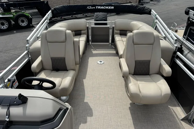 Slide: The Image of 2024 Sun Tracker Party Barge 24 DLX interior with plush seating and steering console. - 5