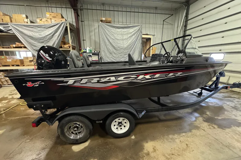 The Image of 2024 Tracker Targa V-18 Combo boat in a garage, featuring sleek design and Mercury engine. - 0