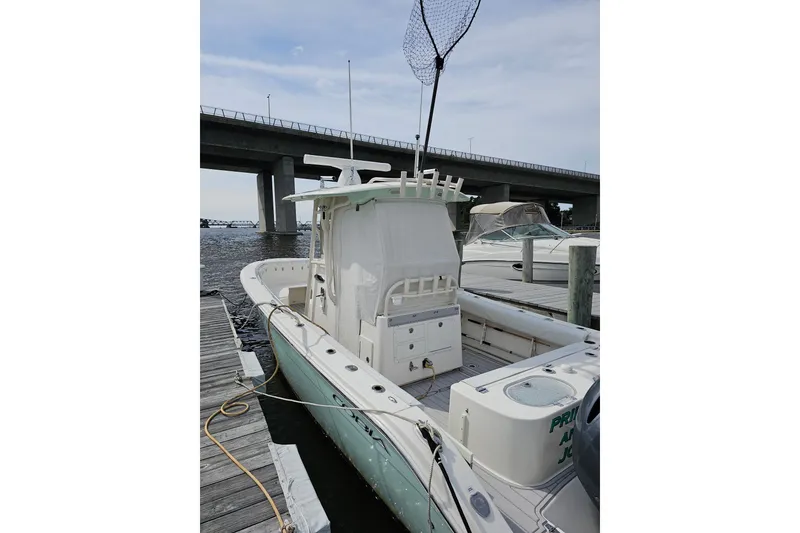 Slide: The Image of 2017 Cobia 277 Center Console boat docked near a bridge on a sunny day. - 2