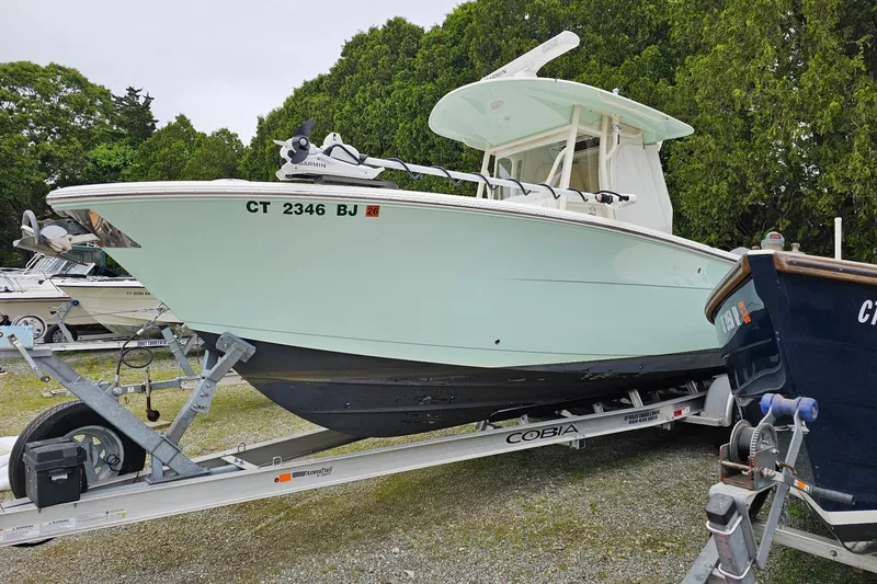 Slide: The Image of 2017 Cobia 277 Center Console boat on trailer, surrounded by trees. - 3