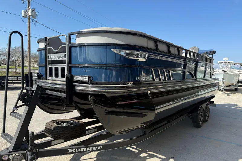 Slide: The Image of 2020 Ranger 2300LS pontoon boat on trailer, parked outdoors under clear blue sky. - 4