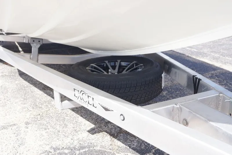 Slide: The Image of 2026 Excel 230 Bay Pro Elite boat trailer with spare tire on pavement. - 18