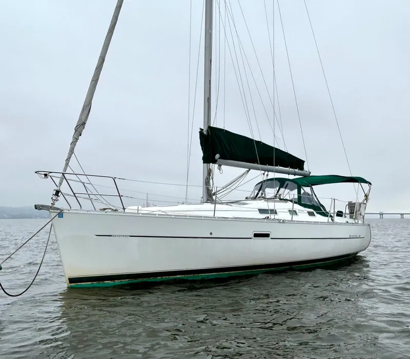 Slide: The Image of 2005 Beneteau 323 sailboat docked in marina, featuring green canopy and white hull. - 2