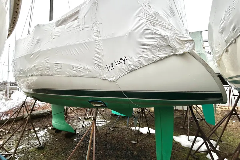 Slide: The Image of 2005 Beneteau 323 sailboat in dry dock, covered and supported by stands. - 25