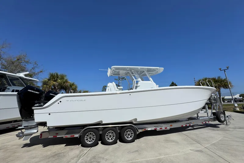Slide: The Image of 2026 Invincible 33 Catamaran on trailer, sleek design, dual Mercury engines, clear blue sky. - 11