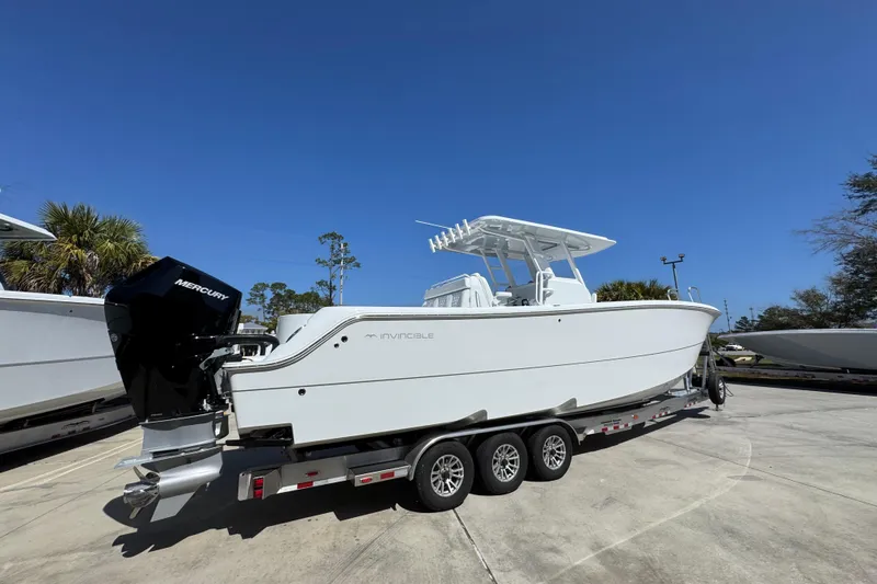 Slide: The Image of 2026 Invincible 33 Catamaran on trailer, featuring Mercury outboard engine, under clear blue sky. - 12