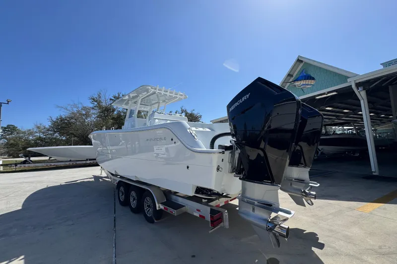 Slide: The Image of 2026 Invincible 33 Catamaran with dual Mercury engines on a trailer, under clear blue sky. - 17