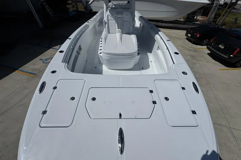 Slide: The Image of 2026 Invincible 33 Catamaran with sleek white deck and seating, parked in a marina. - 19