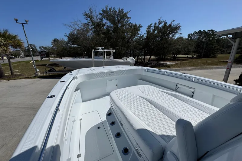 Slide: The Image of 2026 Invincible 33 Catamaran with white seating, docked outdoors under clear blue sky. - 22