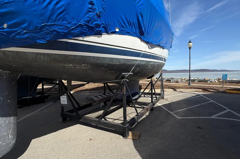 Slide: The Image of Covered 2005 Hunter 38 sailboat on a stand by a waterfront parking area. - 10