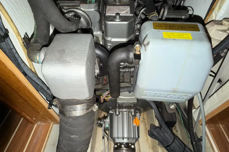 Slide: The Image of Engine compartment of a 2005 Hunter 38 sailboat, showcasing mechanical components and wiring. - 26